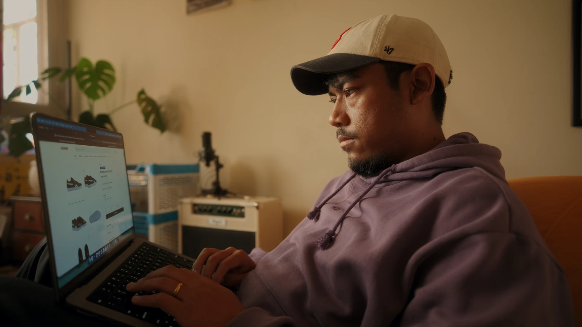 Ajay in a cap, working on his laptop in warm light