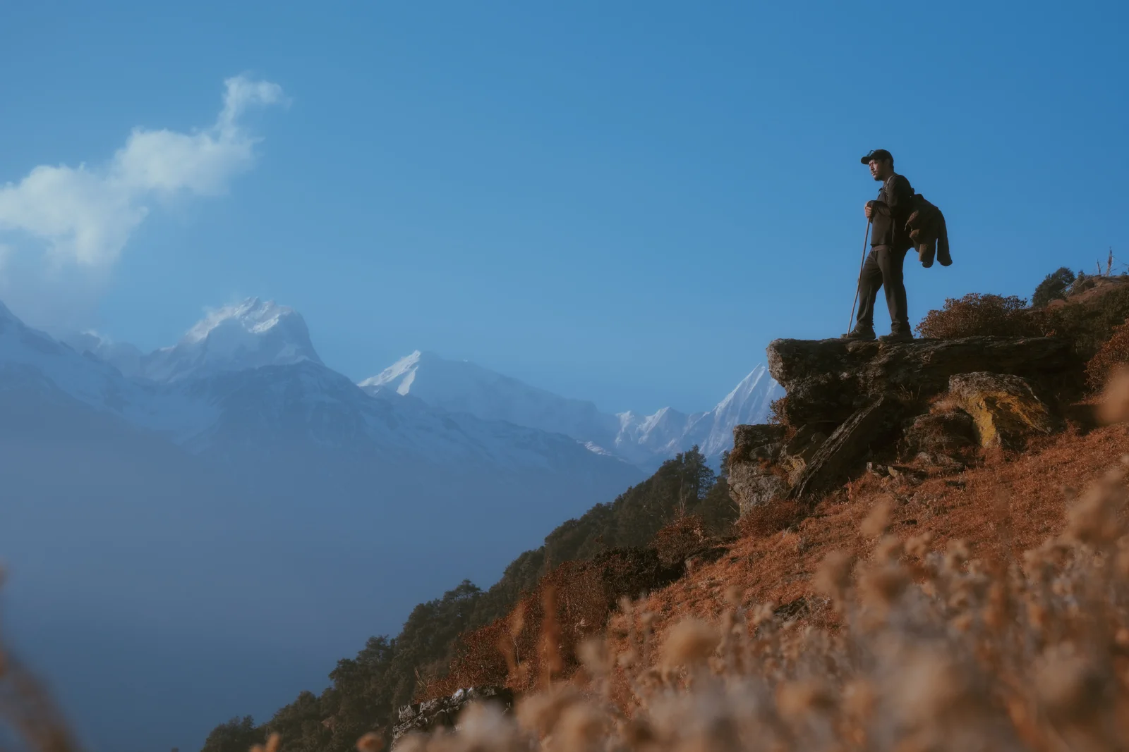 Ajay on a mountain ridge above the clouds, Himalayan peaks behind him